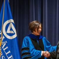 Provost Mili smiles and shakes hands with woman